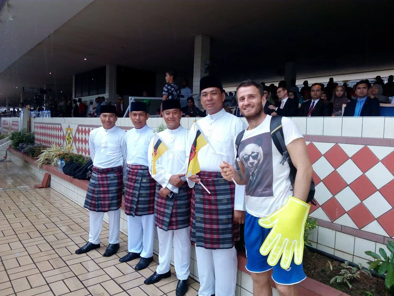 Danny with Bruneian men in traditional dress holding flags