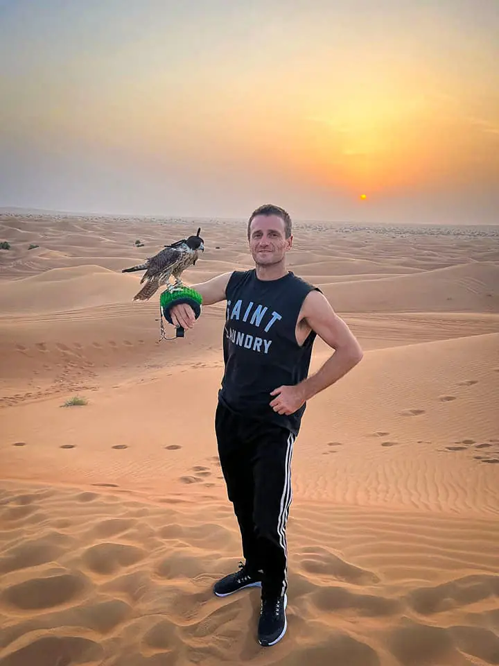 Danny holding a falcon in the desert at sunset