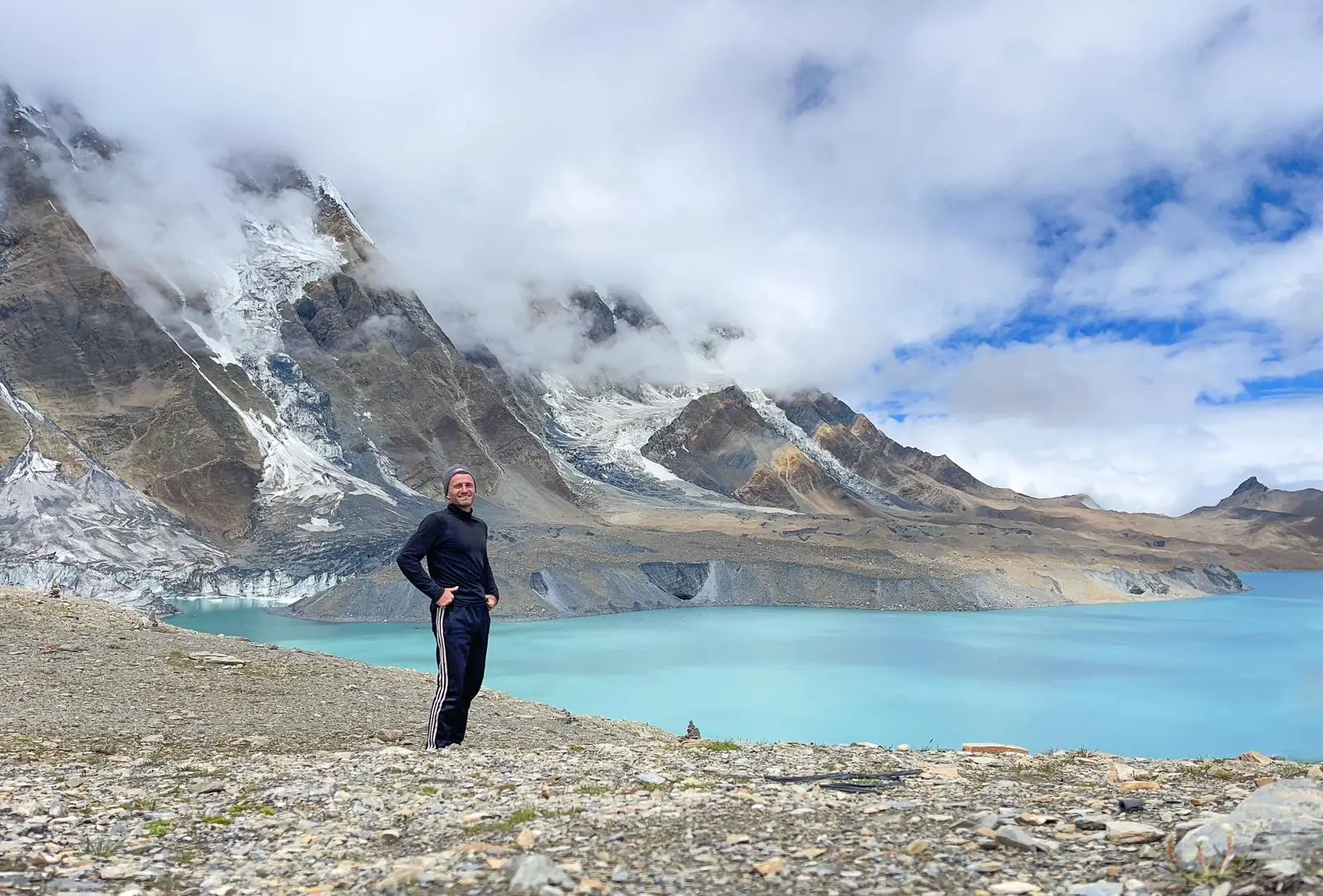 Danny beside a glacial lake below Himalayan peaks