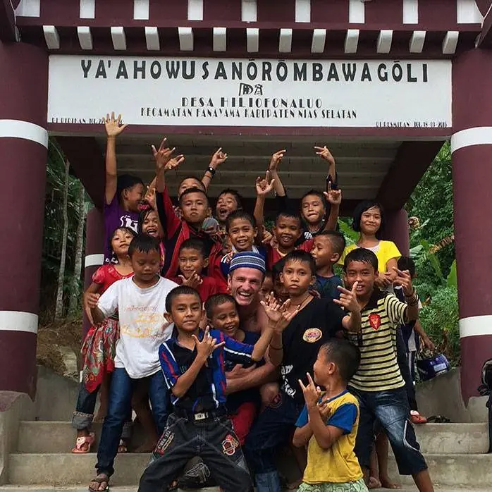Danny with a crowd of cheering children under a village gate