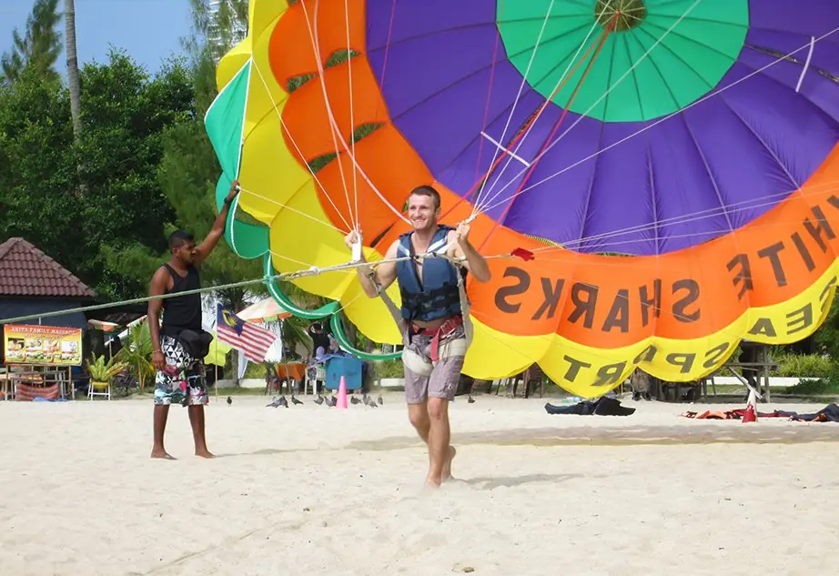 Danny landing after parasailing on a beach